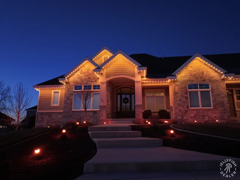 The same home with warm roofline lighting switched on