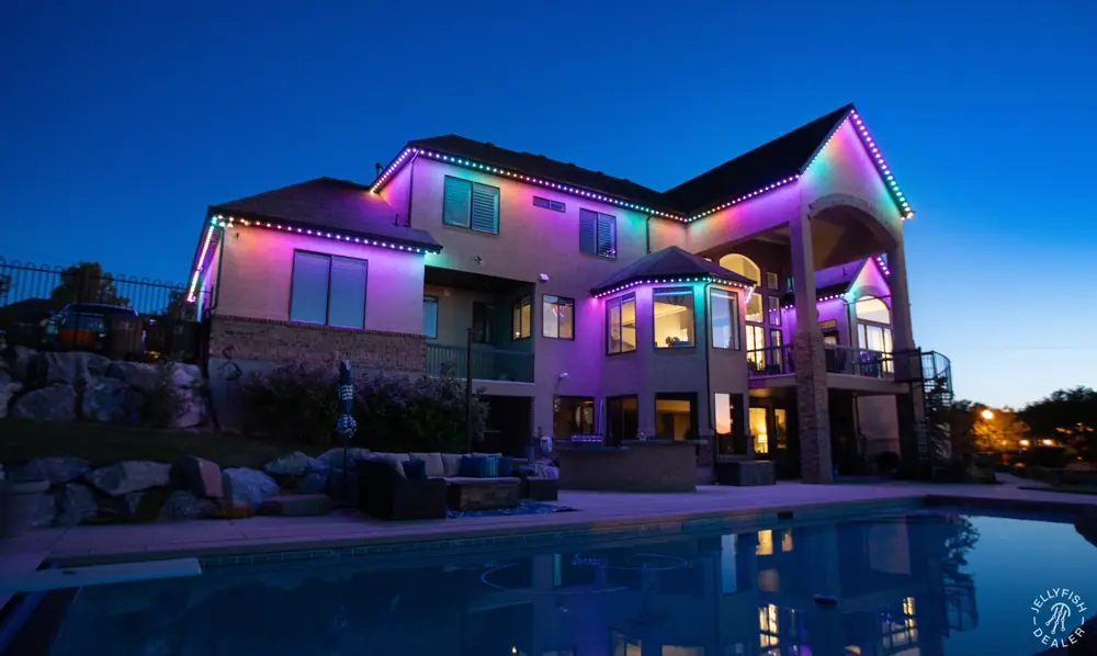 Home above a pool with multicolor roofline lighting