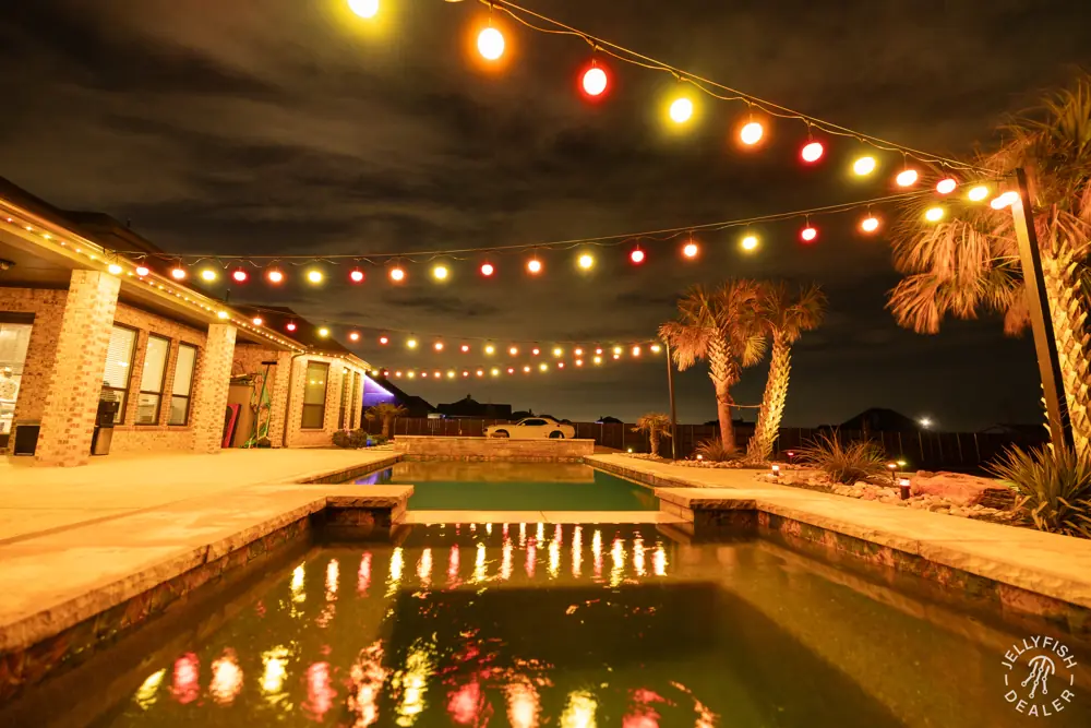Pool and patio with warm string lights and palm trees
