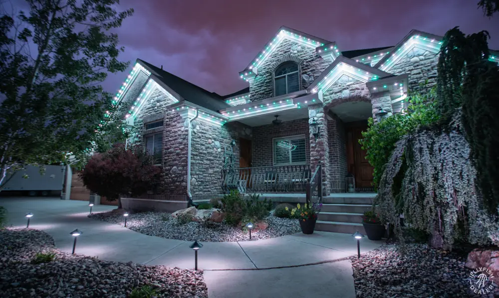 Home with white roofline lights and pathway lights along the walk